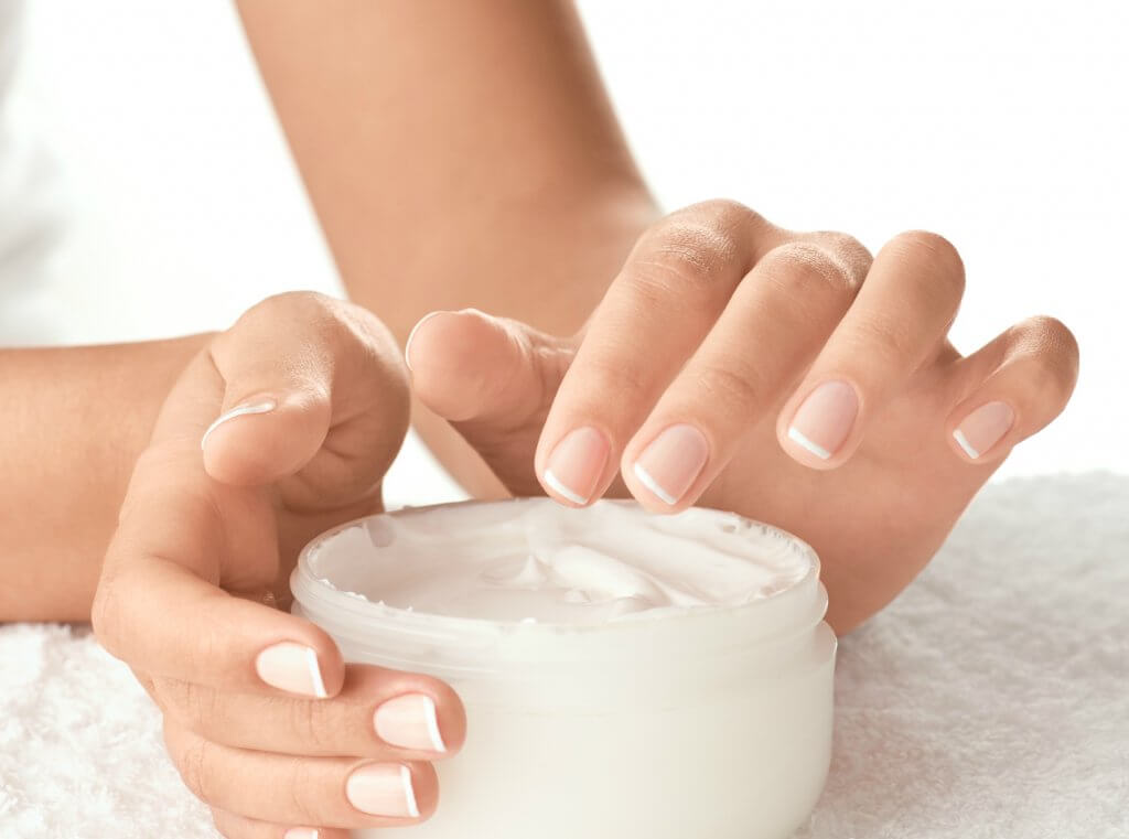 mãos femininas segurando e pegando o creme redutor de medidas do pote